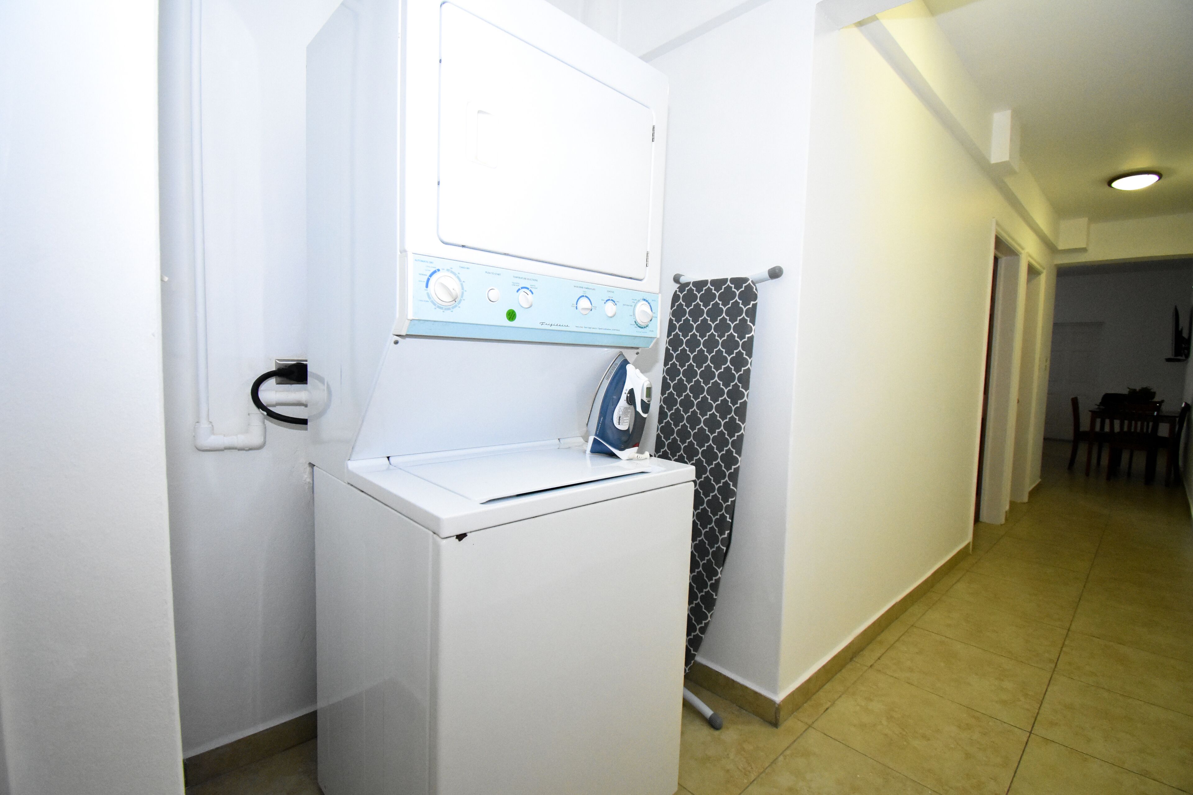 Een kleine wasruimte met een wasmachine en droger, een handdoekrek en een douchegordijn met een patroon.