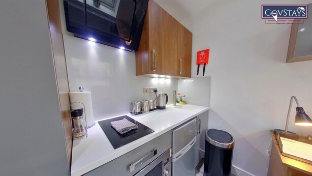 A compact kitchen with modern appliances, a sink, and a trash bin. - Victoria House - Classic Studios by CovStays (Coventry)