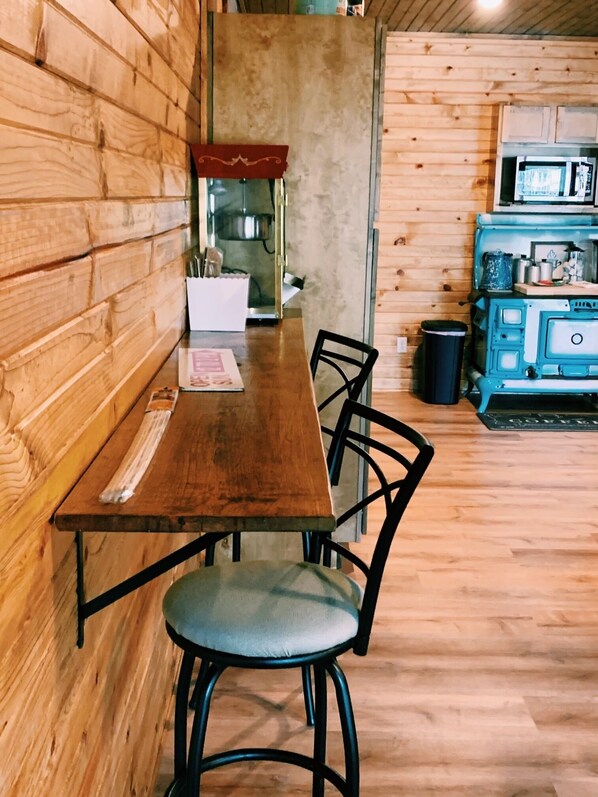 Un interior de madera con una mesa larga y sillas, un microondas y un cubo de basura.