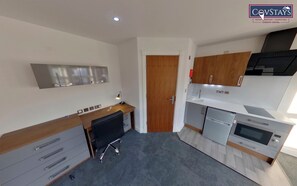 A modern kitchen with stainless steel appliances, wooden cabinets, and a grey carpet.