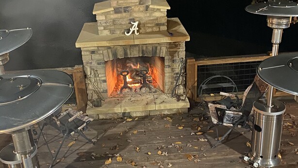 An outdoor stone fireplace with a chimney, surrounded by metal tables and chairs. - Remote Cabin with all amenities  (Lutts)