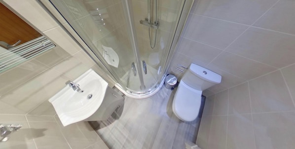 A bathroom with a glass-enclosed shower, a white sink, and a toilet.