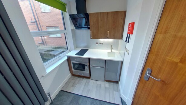 A compact kitchen with a window, built-in oven, and a microwave.