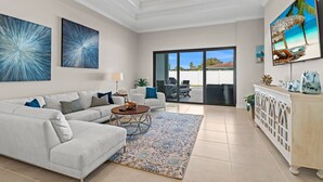 A spacious living room with a white sofa, a coffee table, and a large window offering a view of the outdoors. - LimitedTime Special Offer  New Vanderbilt Beach Home Heated Saltwater Pool & Spa (Naples)