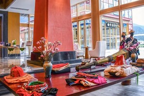 Eine Lobby mit einer Rezeption, einer großen Vase mit Blumen und traditioneller Einrichtung.
