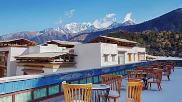 A hotel with outdoor seating and a view of snow-capped mountains.