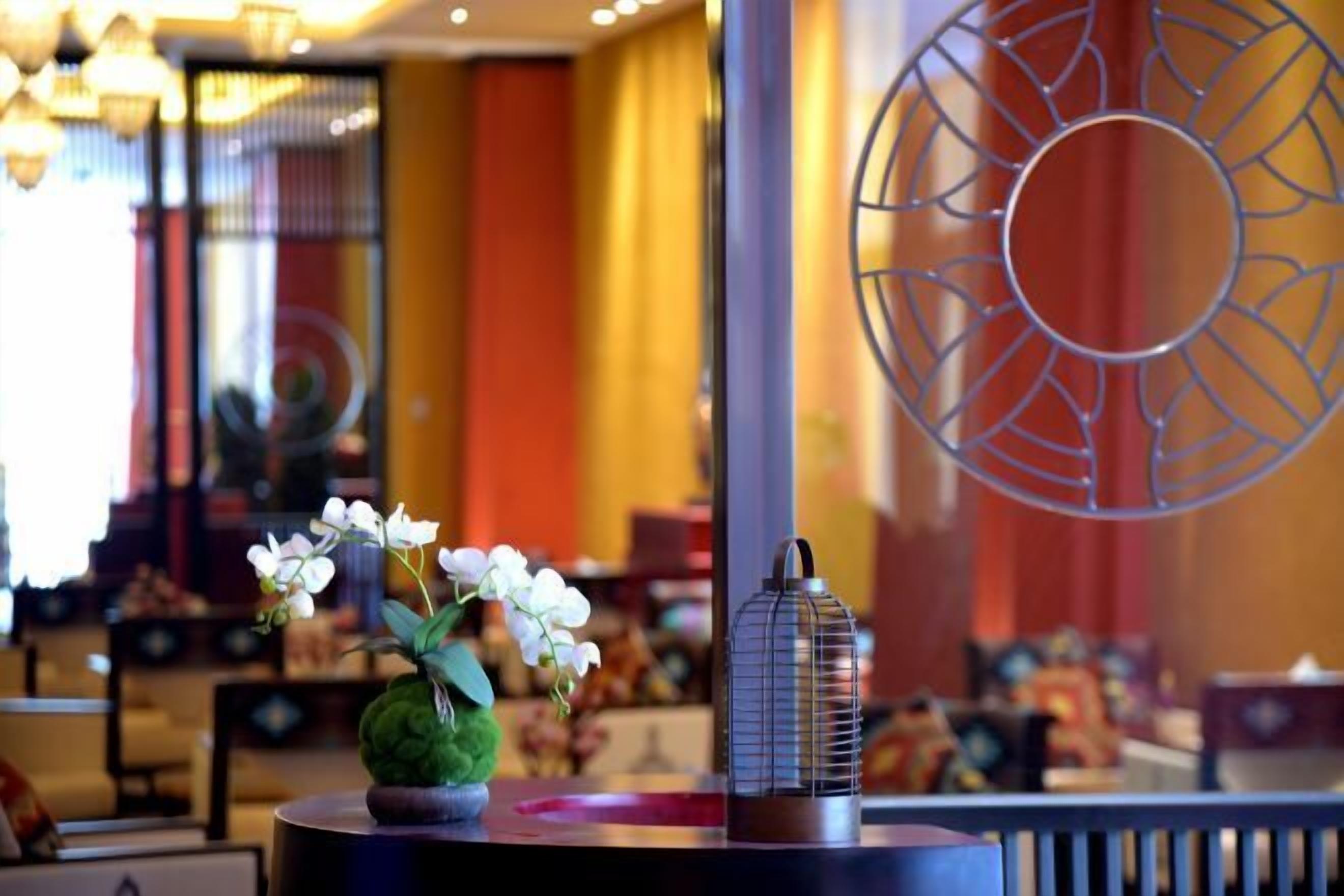 A room with a round table, a potted plant, and a decorative metal piece.