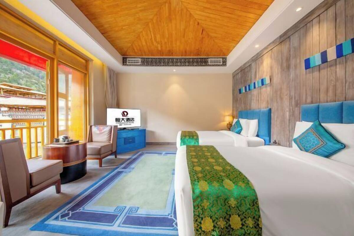 A hotel room with a large bed, a sofa, a desk, and a view of a traditional building outside.