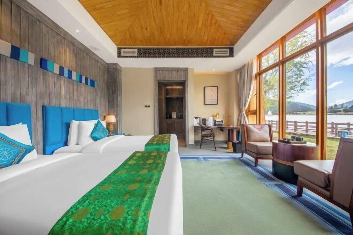A hotel room with a large bed, a desk, and a view of the outdoors.
