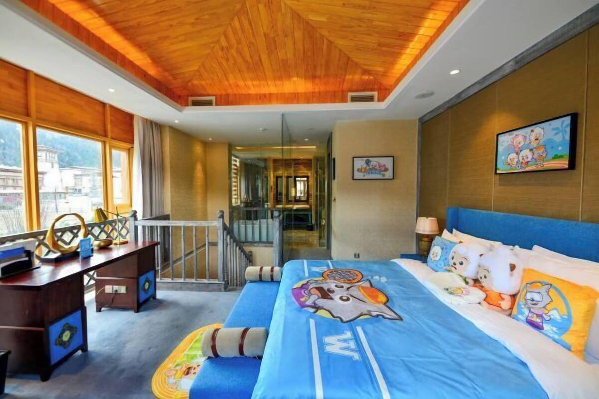 A hotel room with a large bed, a desk, and a view of the outside.