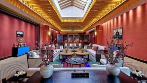A modern hotel lobby with a high ceiling, red walls, and a central seating area with sofas and tables. - Evergrande Hotel, Nyingchi (Nyingchi)