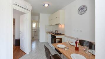 A modern kitchen with white cabinets, a wooden dining table set with plates and glasses, and a wall clock.