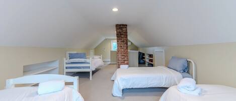 A room with two beds, a brick chimney, and a white ceiling.