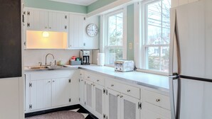 A kitchen with white cabinets, a clock, a toaster, and a refrigerator. - Classic Mystic Retreat Walking Distance to Downtown (Groton)