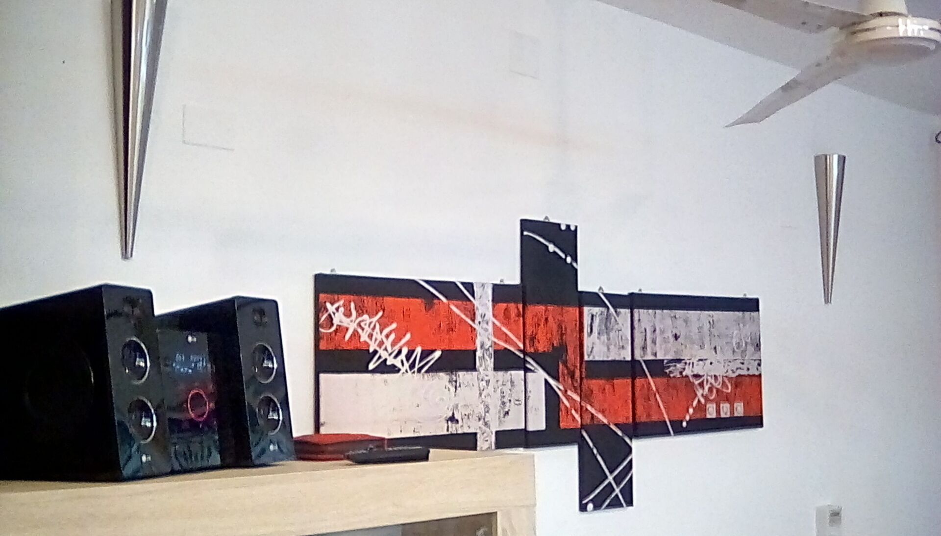 A room with a wooden table, a black speaker, and a large abstract painting on the wall.