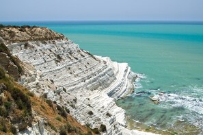 A coastal cliff with layered sedimentary rock formations. - Apartment - Sleeps 3 & Swimming Pool (Realmonte)