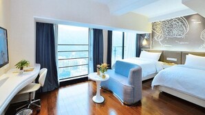 A modern hotel room with a large window, a desk, a sofa, and two beds. - Vienna Apartment (Shenzhen)