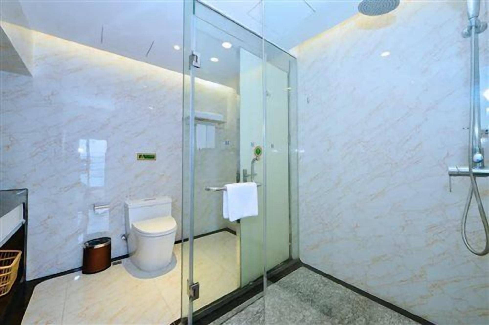 A modern bathroom with a glass-enclosed shower, a toilet, and a sink.