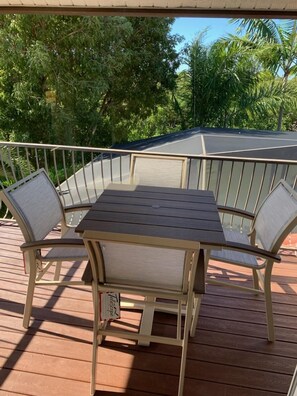 A wooden deck with a table and chairs, surrounded by a metal railing. - Serene Waterfront Home, walk to TigerTail Beach, Pet Friendly, EV Charger (Marco Island)
