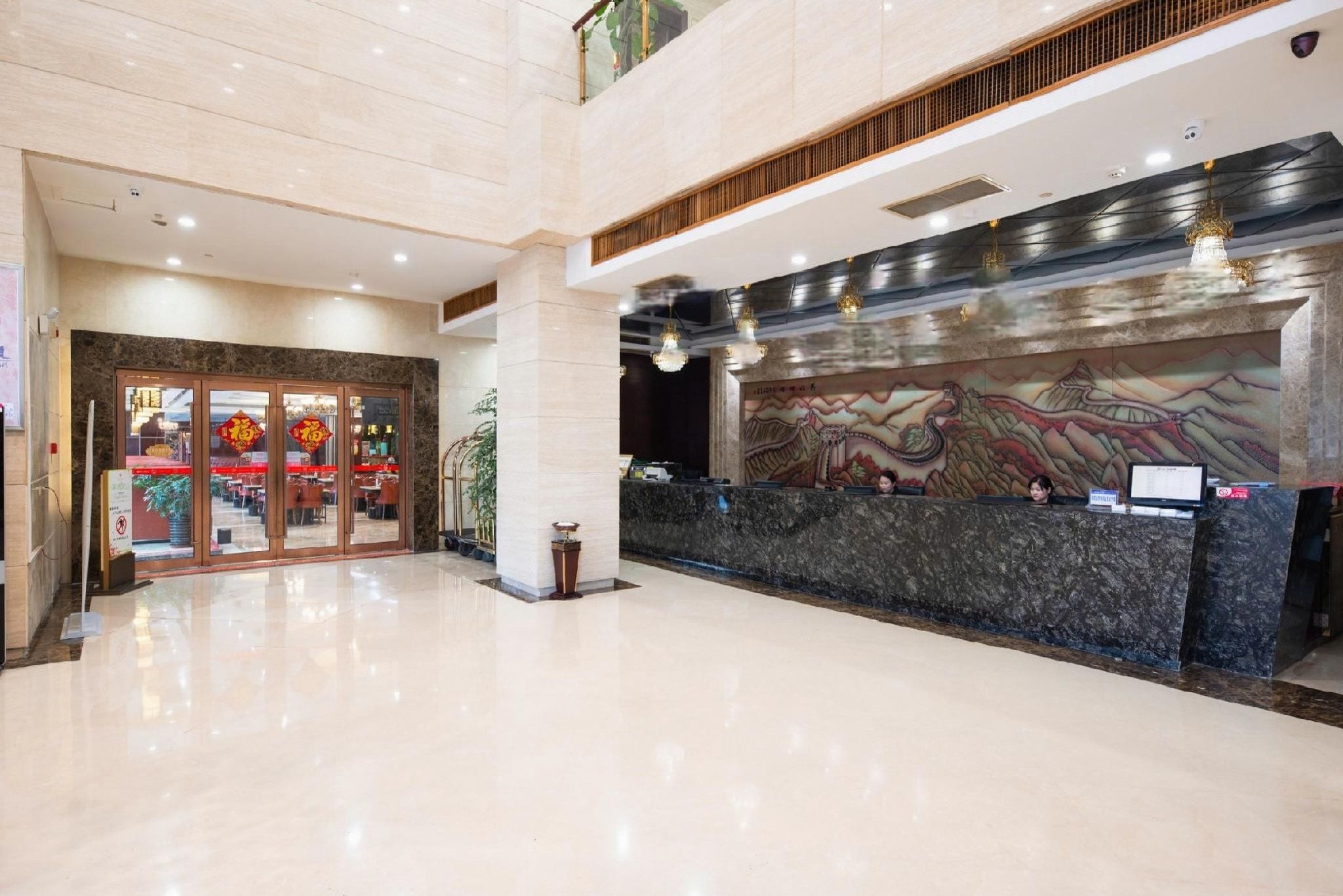 Eine großzügige Lobby mit einer Rezeption, einem großen Wandgemälde und einem Eingang mit Glastür.