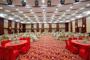 A large conference room with multiple round tables and chairs, a patterned carpet, and a high ceiling with recessed lighting.