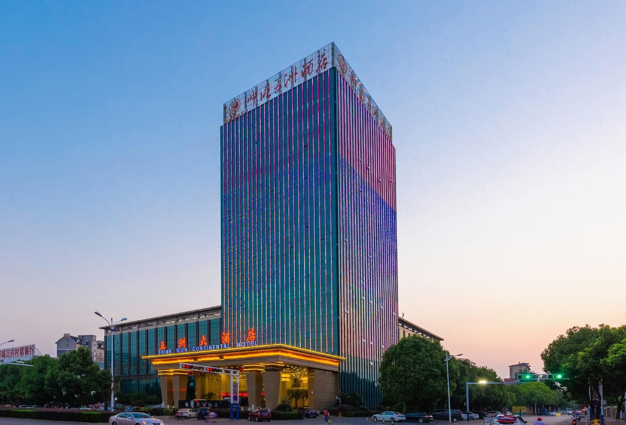 Een hoog hotel met een verticale gevel en een helder verlichte ingang.