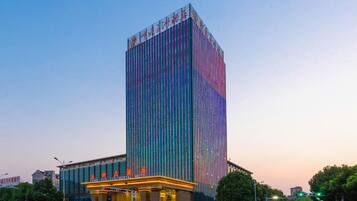 Een hoog hotel met een verticale gevel en een helder verlichte ingang.
