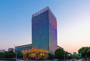 Un hotel alto con fachada vertical y una entrada muy iluminada.