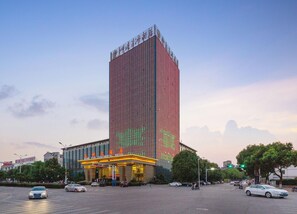 Un hotel alto de diseño moderno, con una entrada destacada y señalización iluminada.