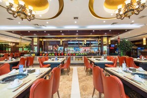 A spacious restaurant with multiple dining tables and chairs, a central bar area, and decorative lighting. - Shinewon Continental Hotel (Lu'an)