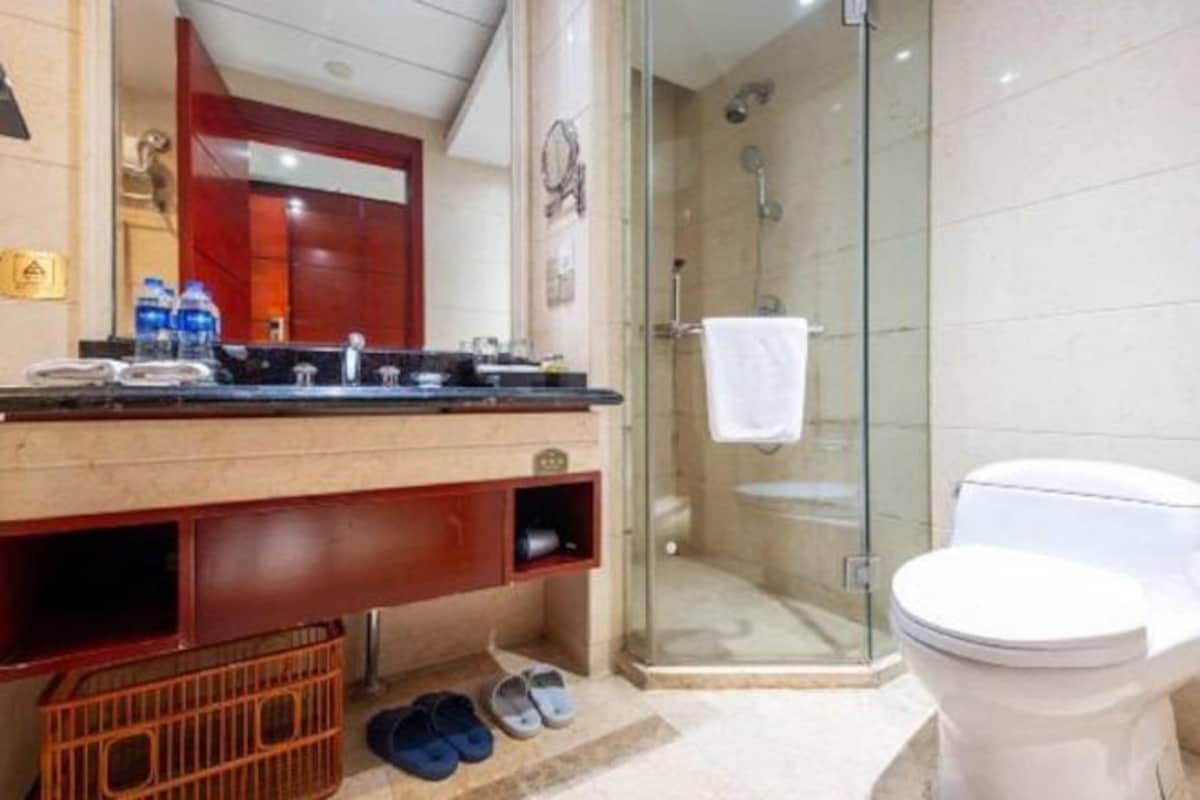 Un baño moderno con ducha envuelta en vidrio, inodoro blanco y tocador con espejo y un mueble rojo.