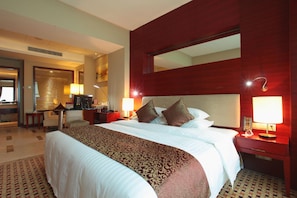 Una habitación de hotel con una cama grande, mesitas de noche, un escritorio y un espejo.