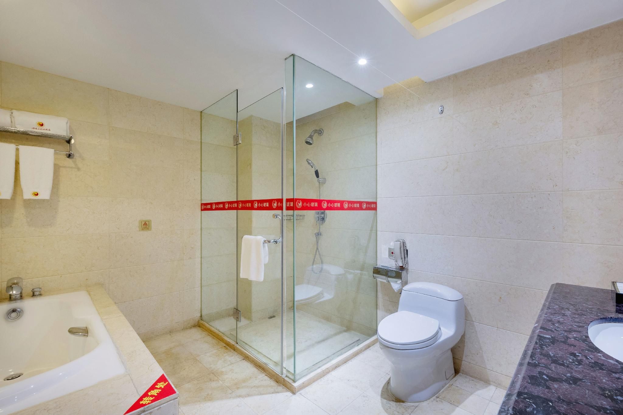 Ein modernes Badezimmer mit einer gläsernen Duschkabine, einer separaten Toilette und einer freistehenden Badewanne.