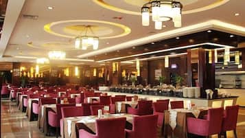 A spacious restaurant with multiple dining tables and chairs, a bar area, and modern lighting fixtures.