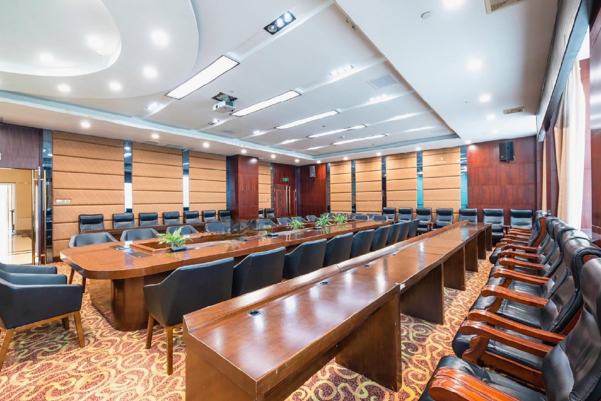 A conference room with a long table, multiple chairs, and a carpeted floor.