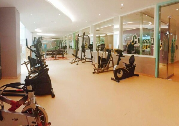 A gym with various exercise equipment including treadmills, stationary bikes, and weight machines.
