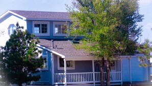 A two-story house with a porch, a garage, and a tree in front. - Country Barn House (Fountain)