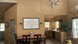 A spacious kitchen with wooden cabinets, a dining area with a table and chairs, and a large wall-mounted deer skull. - Country Barn House (Fountain)