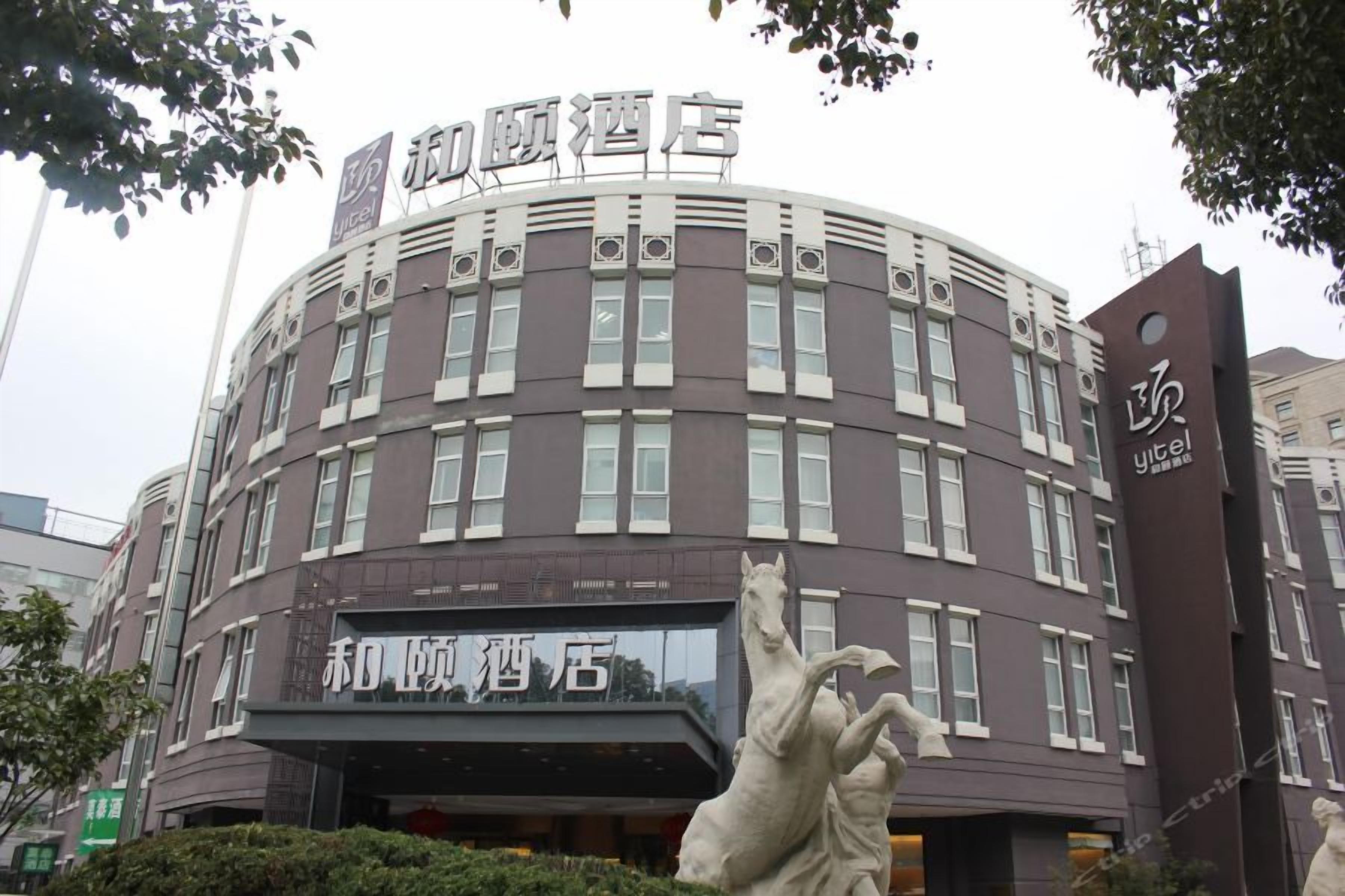 A hotel building with a curved facade, multiple windows, and a prominent entrance with a horse statue.