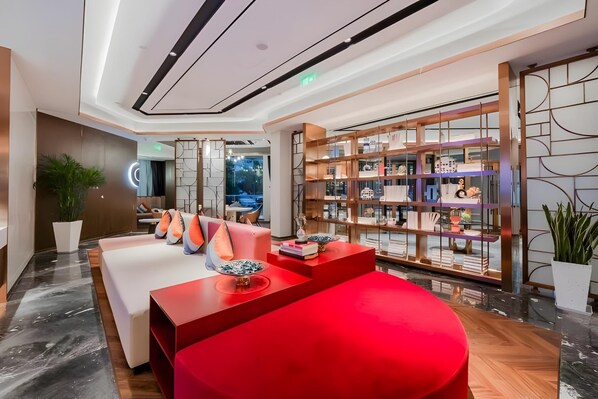 A modern hotel lobby with a red seating area, a glass display case with decorative items, and a large plant. - Yitel (Shanghai)