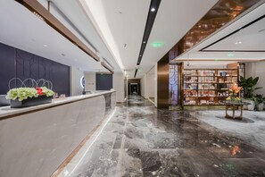 A hotel lobby with a reception desk, a bookshelf, and a marble floor. - Yitel (Shanghai)