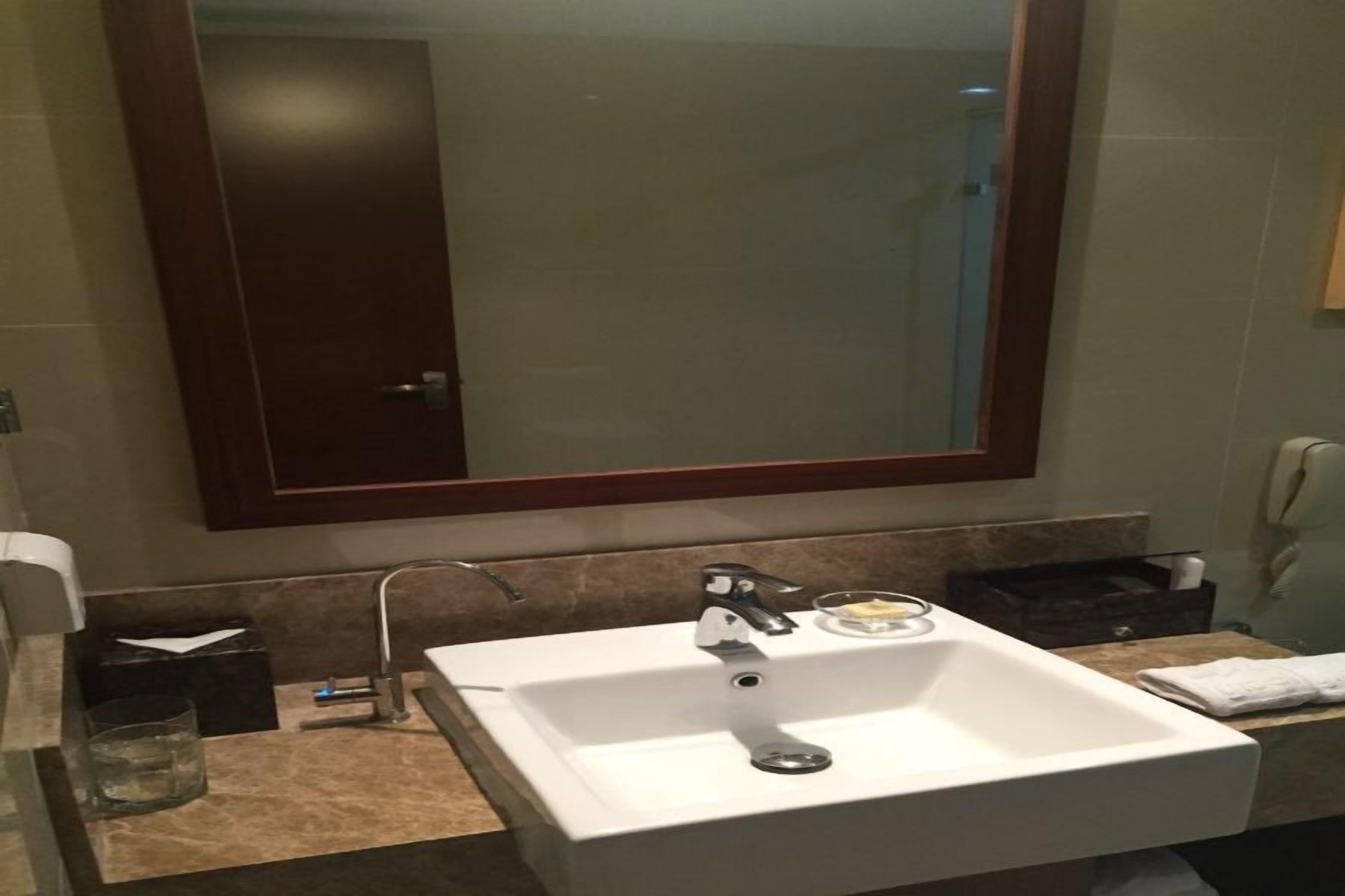 A bathroom with a white sink, a mirror, and a towel rack.