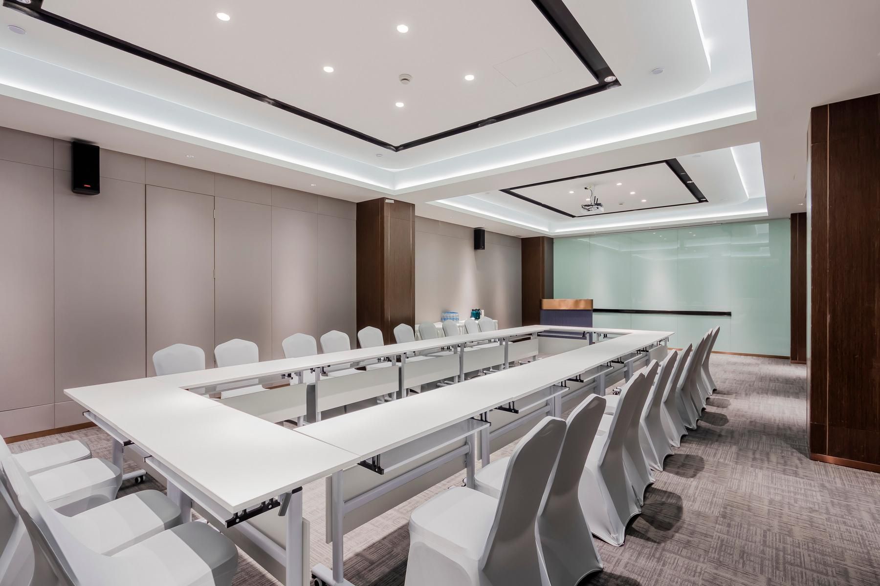 A conference room with a long table, chairs, and a presentation screen.