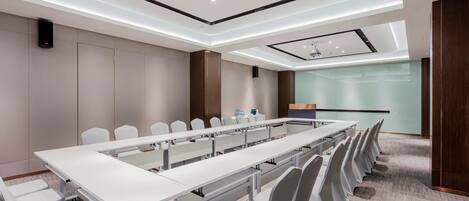 A conference room with a long table, chairs, and a presentation screen.