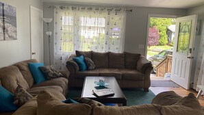 Ein Wohnzimmer mit zwei braunen Sofas, einem Couchtisch und Blick ins Freie.