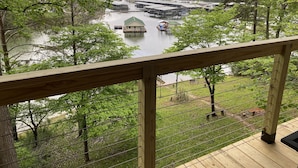 Une terrasse en bois offrant une vue sur une rivière, des bateaux et une côte lointaine.