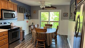 Une cuisine avec des meubles de rangement en bois, un four à micro-ondes, un four traditionnel et une table à manger avec des chaises.