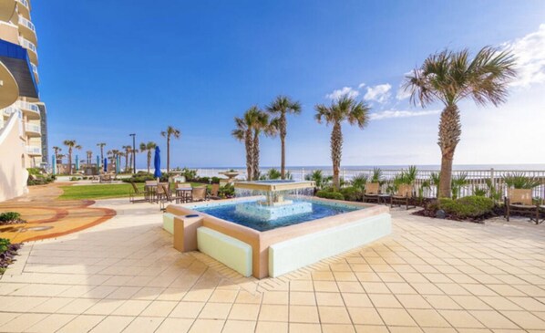 Relax by the oceanfront pool, surrounded by lounge chairs and palm trees.