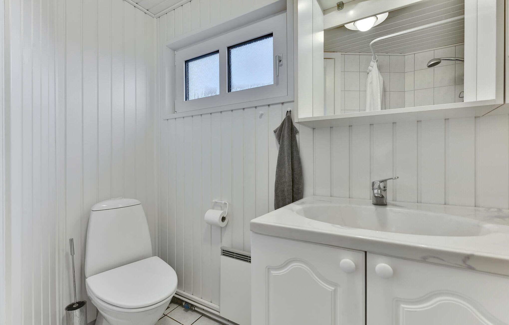 Une salle de bain avec des toilettes, un lavabo et une fenêtre.