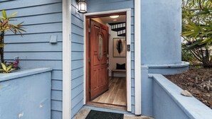 A house entrance with a wooden door, a light fixture above it, and a small porch area with plants. - New! Refreshing Beach Getaway- Heart of San Diego! (San Diego)